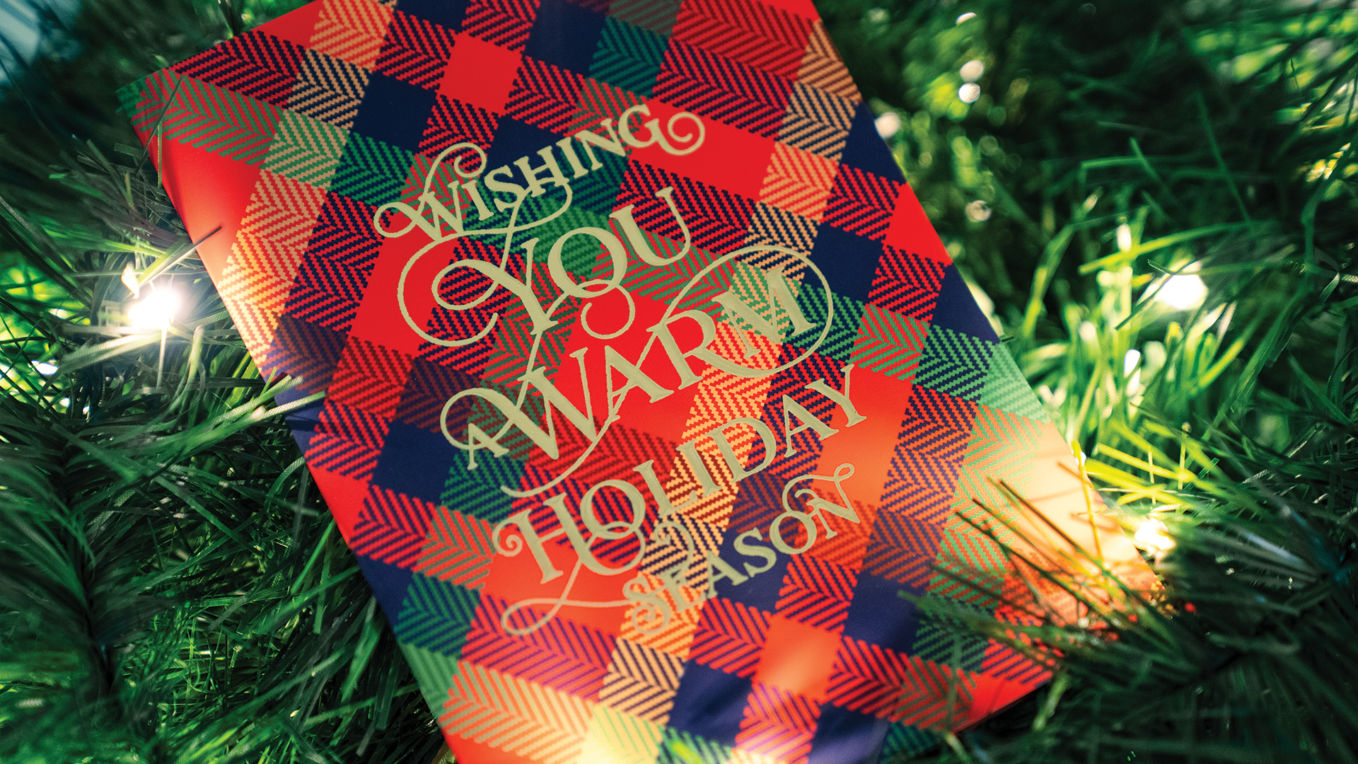 Flannel-patterned holiday card against a Christmas tree