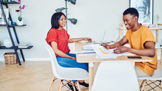 Two designers at a table looking at sheets of papers