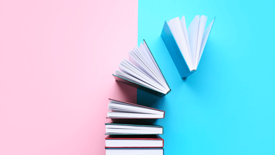 Differently colored books against a pink and blue surface