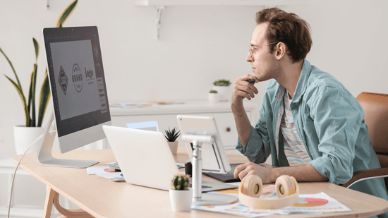 Designer at his desk comparing logos on a computer