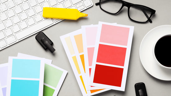 A photo of several papers on a desk that have shades of colors printed on them