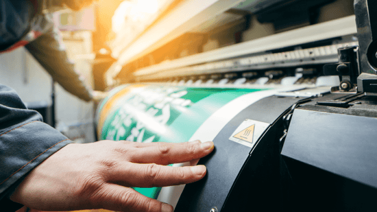 hand touching a printed poster coming out of a large format printer