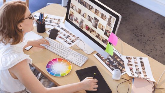 woman at a desk working on a iMac with a color wheel on the desk